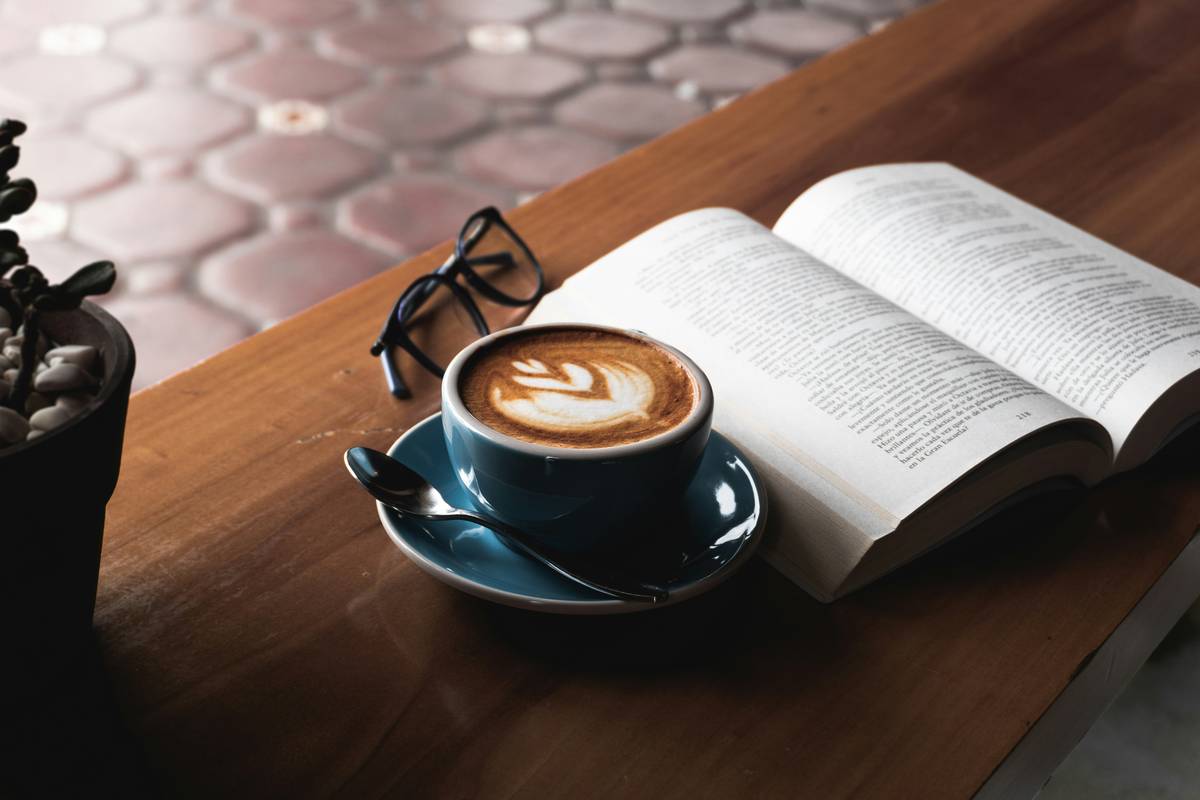 A coffee and an open book on a wooden table